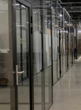 Glass-walled office cubicles with black metal frames and doors.